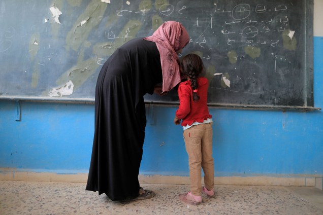 Professora ensina aluna em seu primeiro dia de aula, em uma escola na cidade de Raqqa, Síria - 21/08/2017