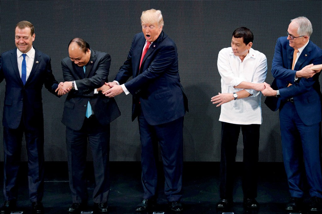 U.S. President Donald Trump registers his surprise as he realizes other leaders, including Russia's Prime Minister Dmitry Medvedev, Vietnam's President Tran Dai Quang, President of the Philippines Rodrigo Duterte and Australia's Prime Minister Malcolm Turnbull, are crossing their arms for the traditional "ASEAN handshake" as he participates in the opening ceremony of the ASEAN Summit in Manila, Philippines November 13, 2017. REUTERS/Jonathan Ernst