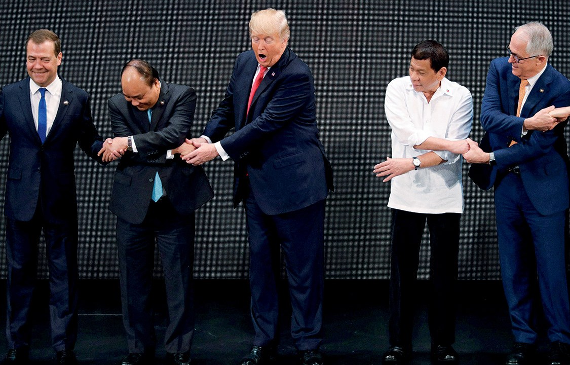 U.S. President Donald Trump registers his surprise as he realizes other leaders, including Russia's Prime Minister Dmitry Medvedev, Vietnam's President Tran Dai Quang, President of the Philippines Rodrigo Duterte and Australia's Prime Minister Malcolm Turnbull, are crossing their arms for the traditional "ASEAN handshake" as he participates in the opening ceremony of the ASEAN Summit in Manila, Philippines November 13, 2017. REUTERS/Jonathan Ernst