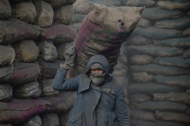 Um carvoeiro descarrega um saco de carvão de um caminhão em uma fábrica na cidade de Cabul, capital do Afeganistão - 13/11/2017