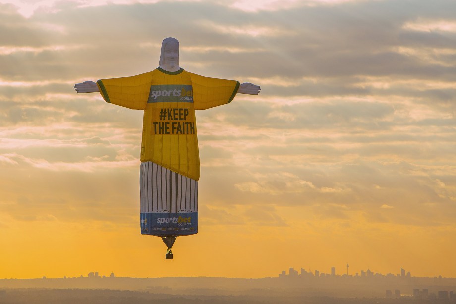 Uma representação do Cristo Redentor inflável é vista durante o pôr do sol no céu da cidade de Sidney, na Austrália. O boneco é parte de uma campanha publicitária em uma empresa de apostas online - 13/11/2017
