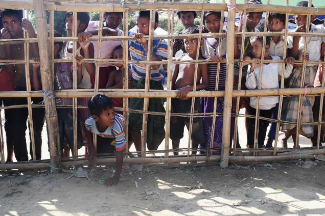 Jovens muçulmanos rohingyas ficam atrás de uma barricada de bambu para coletar comida cozida no campo de refugiados de Thankhali, no distrito de Ukhia, em Bangladesh - 10/11/2017