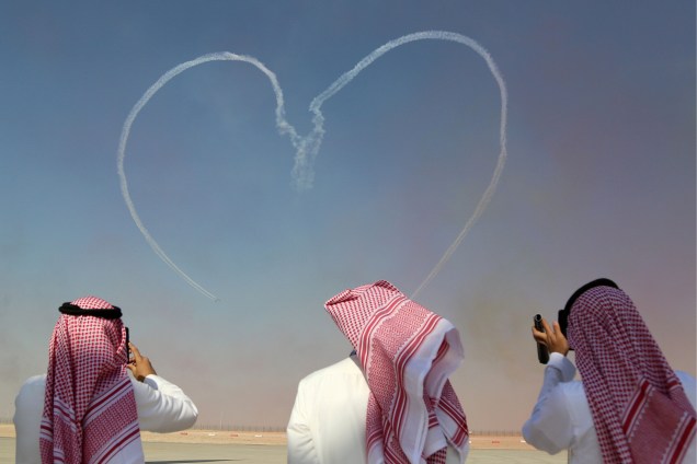 Pessoas fotografam enquanto a equipe de acrobacias aéreas Al Fursan, da Força Aérea dos Emirados Árabes Unidos, atua durante o festival Dubai Airshow, em Dubai - 13/11/2017