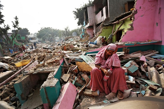 Mulher se senta entre escombros de sua casa, que foi destruída pelas autoridades locais em tentativa de mudar os moradores de local, em Deli, na Índia - 02/11/2017