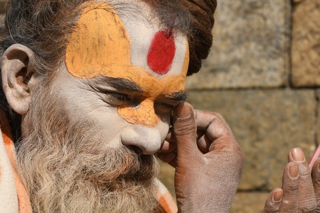 Um devoto hindu Sadhu pinta seu rosto com uma pasta colorida no templo Pashupatinath, em Katmandu, no Nepal. Dezenas de sadhus vivem ao redor do templo dedicando sua vida ao Senhor Shiva, o deus Hindu da destruição - 28/11/2017