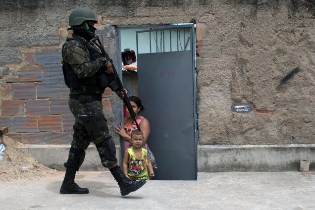 Soldado do exército passa por uma criança, durante operação na favela de Barbante no Rio de Janeiro, onde no início da semana traficantes destruíram um posto policial - 30/11/2017