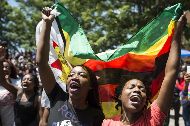 Mulheres ostentam bandeira do Zimbábue durante protesto na Universidade do Zimbábue, reivindicando a retirada do título de doutora da primeira-dama Grace Mugabe, em ato contra a ditadura que dura 37 anos - 20/11/2017
