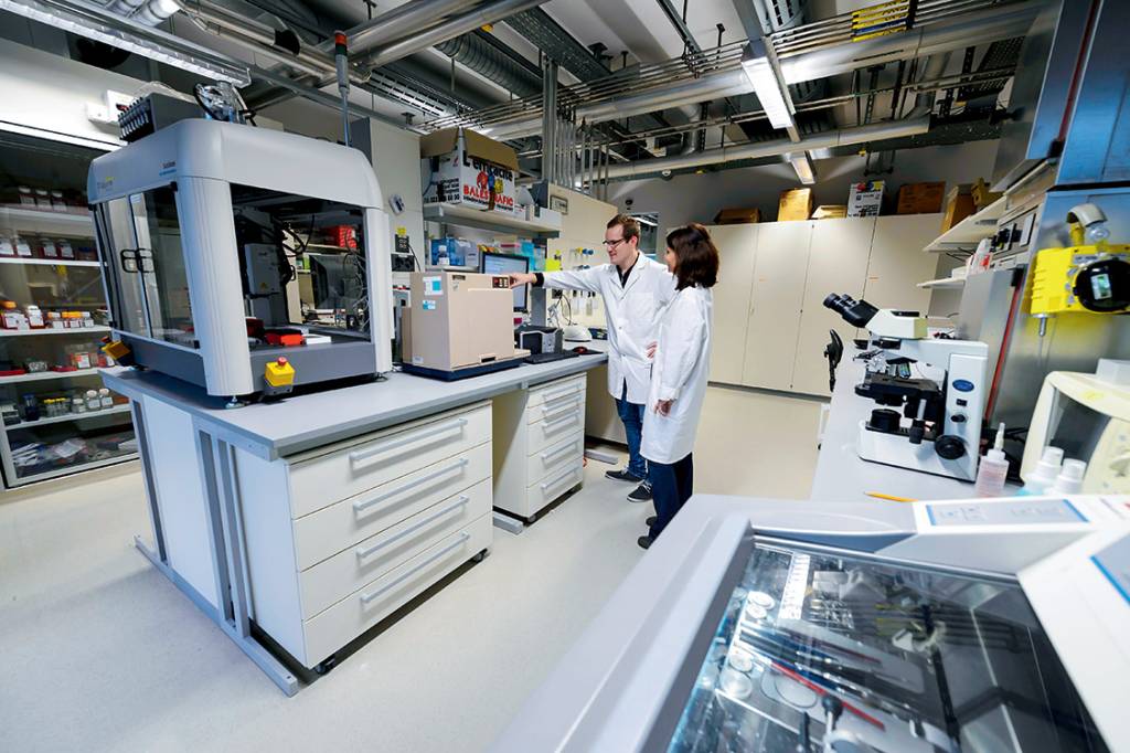 Researchers in a laboratory are seen during a press visit at Campus Biotech on November 4, 2014 in Geneva. A few meters from the international institutions in Geneva, a new research center called Campus Biotech is currently drawing the contours of tomorrow's medicine, research-based and "big data". Based in a huge complex of metal and glass, which housed two years ago the now closed Swiss pharma group headquarters Merck-Serono, the campus has more than 230 researchers currently and is expected to accommodate 600 soon. Credito: FABRICE COFFRINI/AFP PHOTO