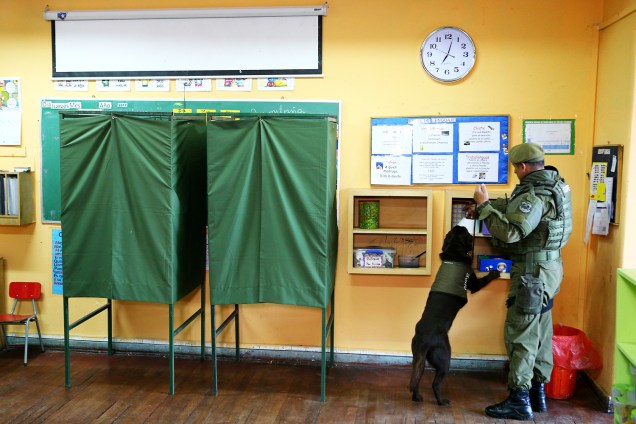 Policial usa cão farejador para inspecionar local de votação, no dia em que ocorre as eleições presidenciais em Santiago, capital do Chile - 19/11/2017