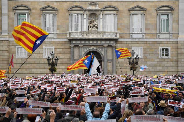 Pessoas levantam cartazes com a frase "Prisioneiros políticos livres" e bandeiras catalãs durante uma manifestação do lado de fora do Palácio da Generalitat, em Barcelona, em uma greve regional convocada pelo movimento pró-independência - 08/11/2017