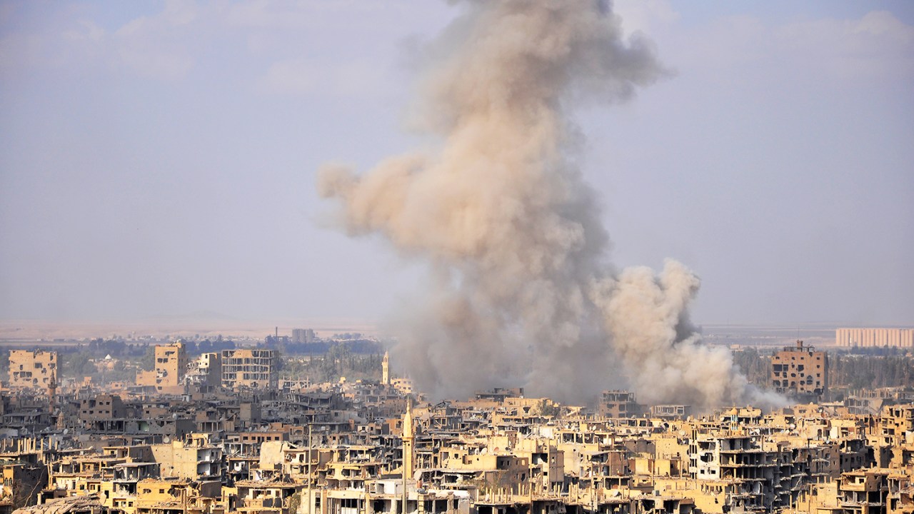 Fumaça é vista entre prédios durante ofensiva do Exército sírio para a retomada do território de Deir Ezzor - 02/11/2017