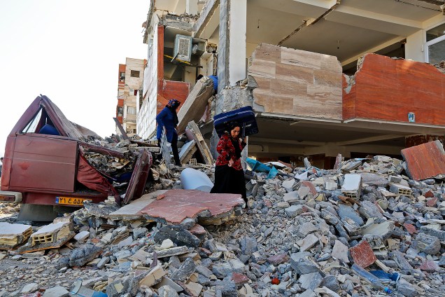 Sobrevivente do tremor carrega pertences para fora de prédios danificados em Sarpol-e Zahab, após terremoto atingir a fronteira entre o Iraque e o Irã - 14/11/2017