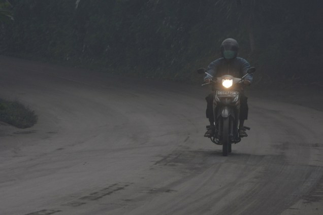 Motociclista atravessa uma estrada coberta de cinzas vulcânicas durante erupção do Monte Agung, em Bali, na Indonésia - 26/11/2017