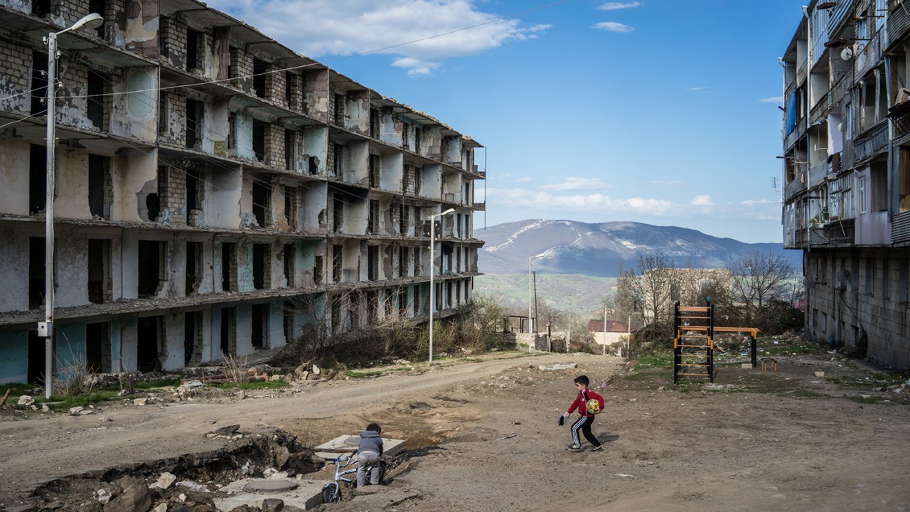 Crianças brincam próximo a um prédio destruído pela guerra, em Nagorno-Karabakh