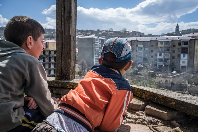 Crianças observam prédios destruídos pela guerra em Artsakh.