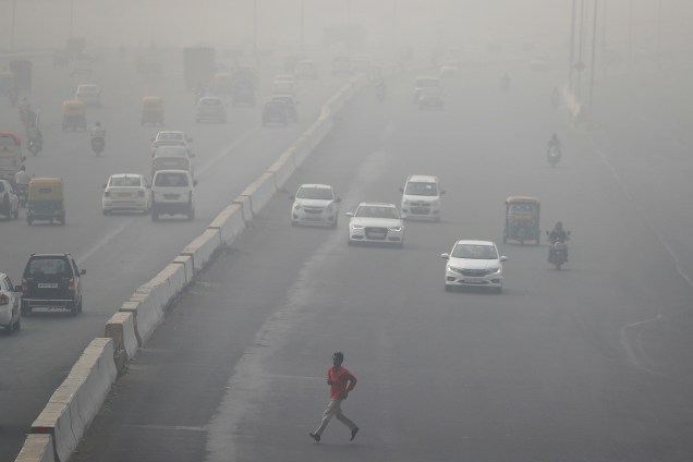 Um homem é fotografado atravessando a rua em meio a densa camada de poluição do trânsito de Nova Deli, na Índia - 13/11/2017