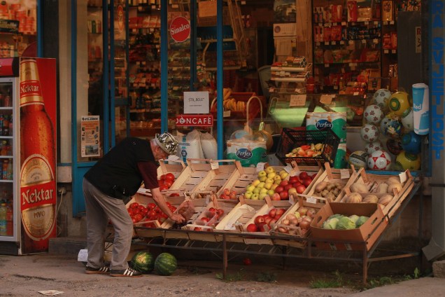 Um homem organiza os alimentos na vitrine de uma mercearia na região da República Srpska, no leste da Bósnia.