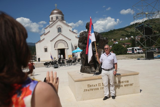 Homem segura bandeira sérvia, na aldeia de Andricgrad, República Srpska.