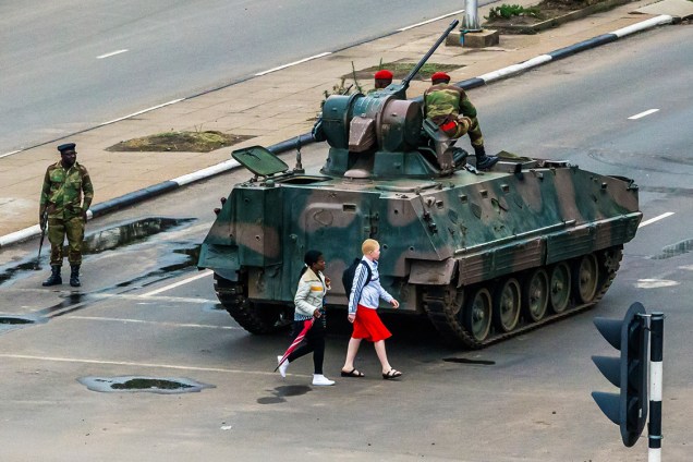 Mulheres caminham próximo a um tanque de guerra, na cidade de Harare, Zimbábue - 15/11/2017