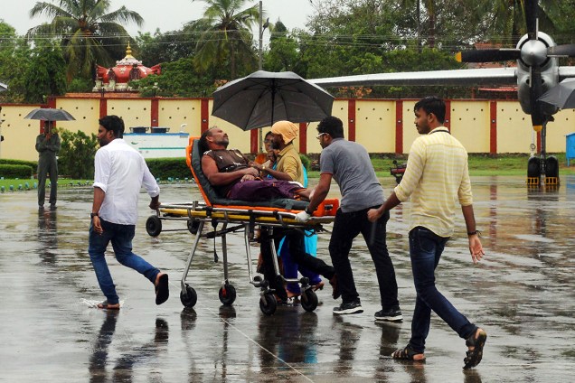 Oficiais carregam pescador que estava perdido no mar por causa do ciclone Ochki que atingiu a costa da Índia