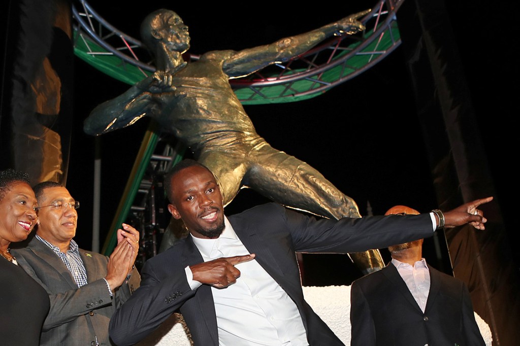 Campeão olímpico, Usain Bolt, posa em frente a estátua em sua homenagem em Kingston, na Jamaica