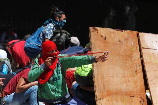 Manifestantes atiram pedras com estilingues durante protesto contra as reformas da previdência social em Buenos Aires, na Argentina