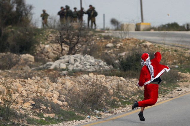 Manifestante vestido de Papai Noel atira pedras em direção à tropas israelenses durante protesto contra a decisão de Donald Trump de mover a embaixada americana em Israel de Tel-Aviv para Jerusalém - 19/12/2017