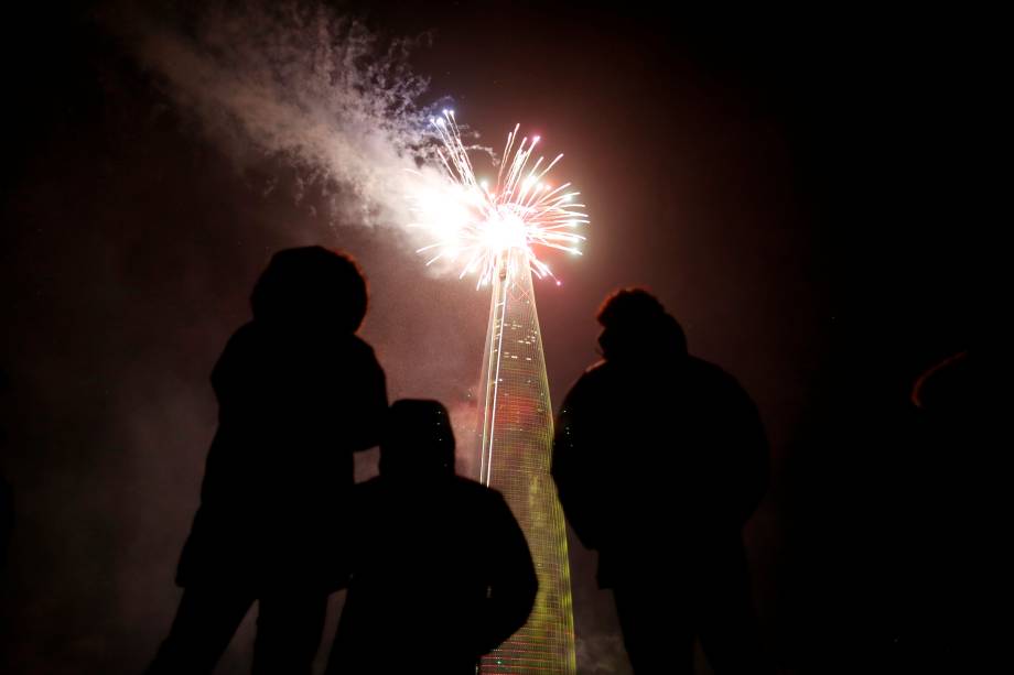 Pessoas acompanham a queima de fogos sobre o arranha-céu de 123 andares Lotte World Tower durante a celebração do Ano Novo em Seul, Coreia do Sul