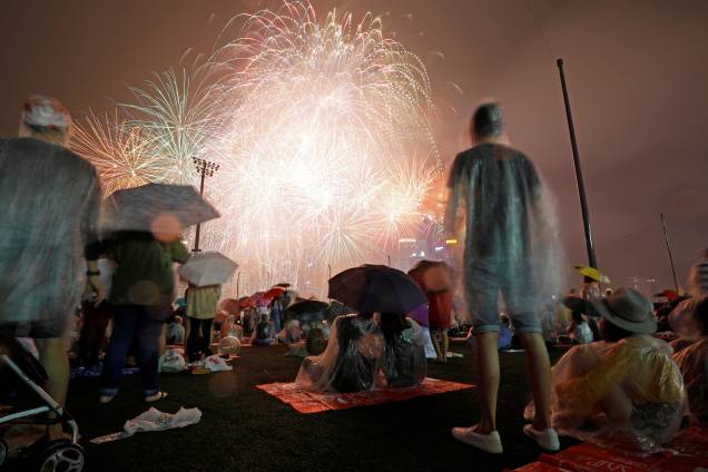 Pessoas vêem fogos de artifício em meio a chuva durante as celebrações do Ano Novo na Marina Bay, em Singapura Pessoas vêem fogos de artifício em meio a chuva durante as celebrações do Ano Novo na Marina Bay, em Singapura