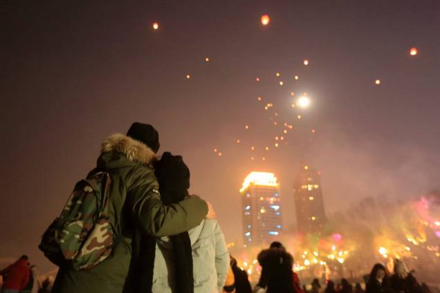 Pessoas observam enquanto lanternas são lançadas ao céu durante as celebrações do Ano Novo no rio Songhua em Harbin, na província de Heilongjiang, na China Pessoas observam enquanto lanternas são lançadas ao céu durante as celebrações do Ano Novo no rio Songhua em Harbin, na província de Heilongjiang, na China