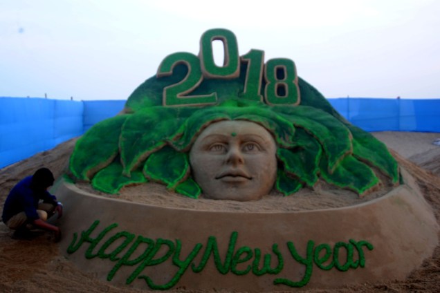 Artista de areia faz escultura para visitantes na costa leste de praia no Golfo de Bengala, na Índia, celebrando o Ano Novo