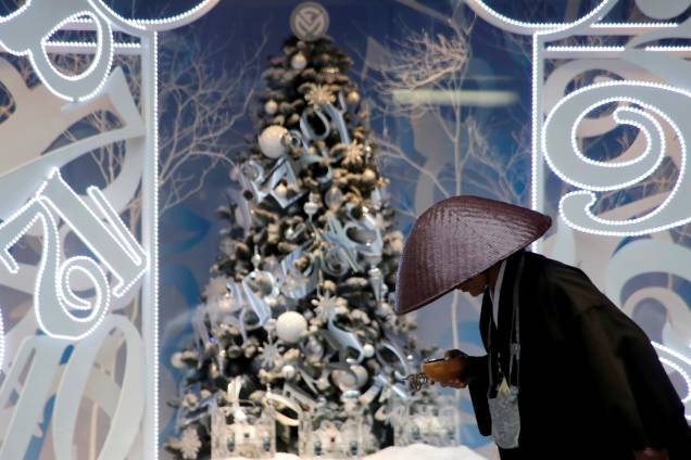 Monge budista se inclina enquanto coleta doações em frente a uma decoração de Natal no distrito comercial Ginza em Tóquio, no Japão - 27/11/2017 Monge budista se inclina enquanto coleta doações em frente a uma decoração de Natal no distrito comercial Ginza em Tóquio, no Japão - 27/11/2017