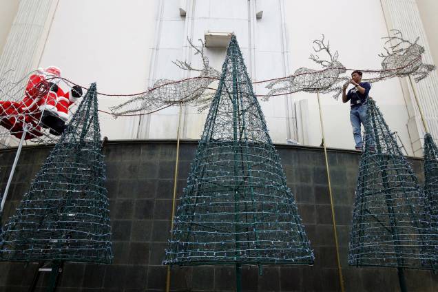Homem decora árvores de Natal em um centro de negócios em Hanói, no Vietnã - 29/11/2017 Homem decora árvores de Natal em um centro de negócios em Hanói, no Vietnã - 29/11/2017