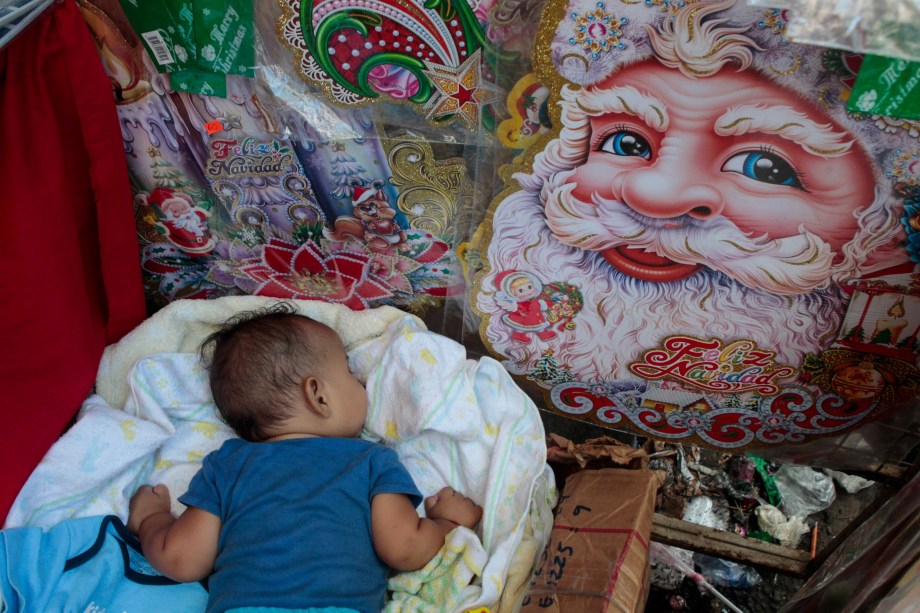 Bebê cercado de decorações de Natal dorme sobre caixa na barraca de sua avó no mercado oriental em Manágua, Nicarágua - 30/11/2017