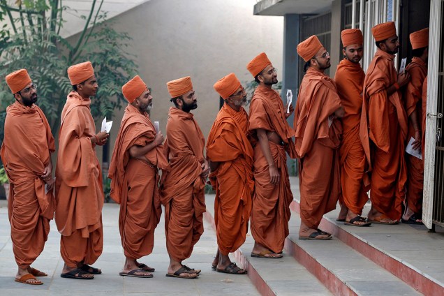 Sacerdotes hindus fazem fila para votarem durante as eleições dos estado de Gujarat, na Índia