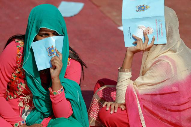 Fiéis utilizam um programa de visitação do Papa Francisco para se proteger do sol durante a missa realizada pelo líder mundial da Igreja Católica Romana em Dhaka, no Bangladesh - 01/12/2017 Fiéis utilizam um programa de visitação do Papa Francisco para se proteger do sol durante a missa realizada pelo líder mundial da Igreja Católica Romana em Dhaka, no Bangladesh - 01/12/2017