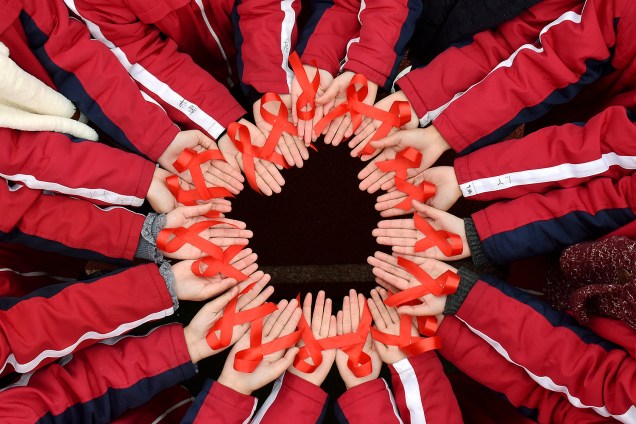 Estudantes chineses seguram fitas vermelhas para marcar o Dia Mundial de Combate à Aids -01/12/2017