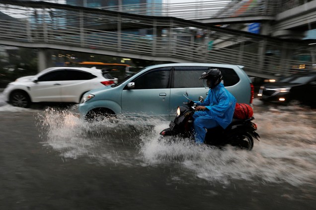 Motociclista tenta atravessar via alagada após chuvas fortes atingirem distrito de Jacarta, na Indonésia - 11/12/2017