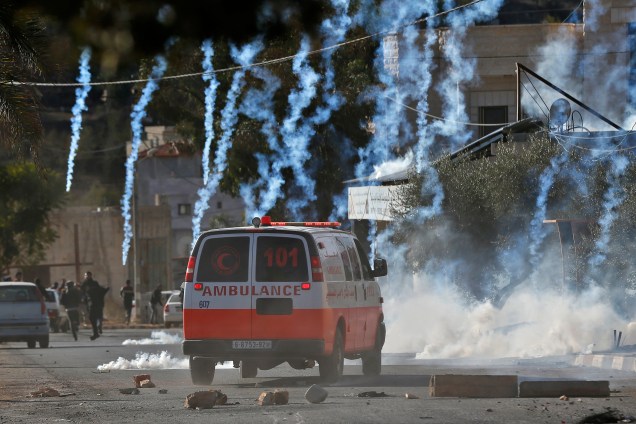 Uma ambulância palestina é vista dirigindo em meio a latas de gás lacrimogênio disparadas por soldados israelenses durante um confronto na aldeia do norte de Qusra, na Cisjordânia ocupada, perto de Nablus - 04/12/2017