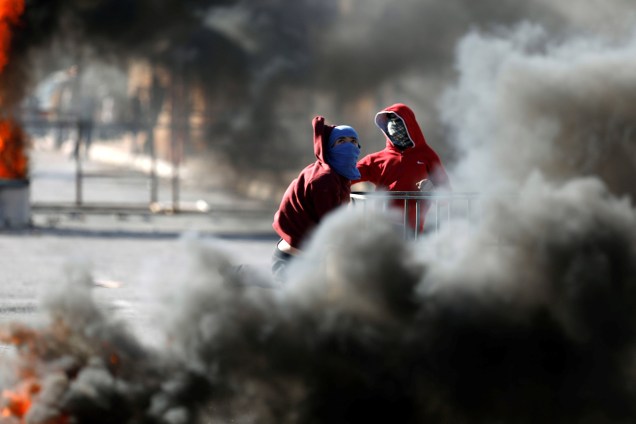 Manifestantes palestinos são vistos em meio a uma nuvem de fumaça durante confrontos com tropas israelenses na aldeia de Qusrah, na Cisjordânia - 04/12/2017