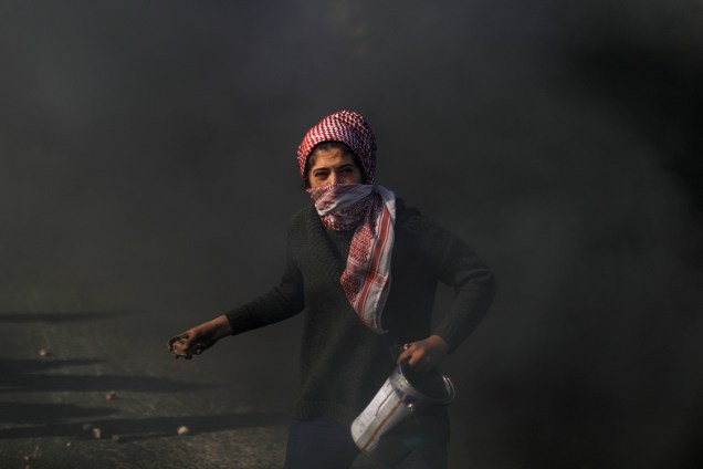 Manifestante palestina atira pedras em tropas israelenses durante protesto contra a decisão dos Estados Unidos de mover a embaixada americana em Israel de Tel-Aviv para Jerusalém - 11/12/2017
