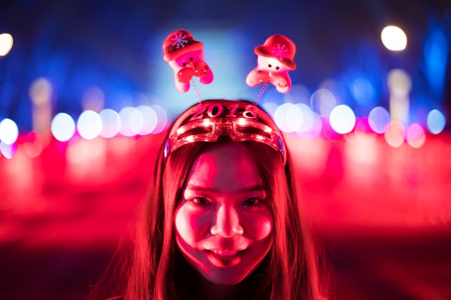 Garota posa para foto antes da tradicional contagem regressiva para a chegada do Ano Novo em Pequim, na China
