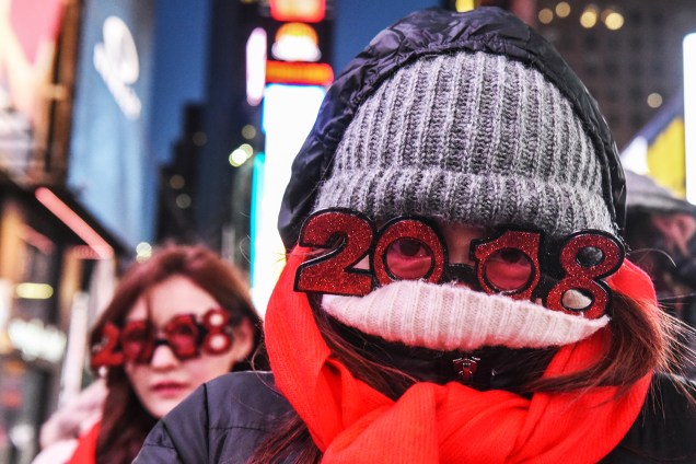Pedestres se protegem das baixas temperaturas enquanto aguardam a chegada do Ano Novo na Times Square, nos Estados Unidos