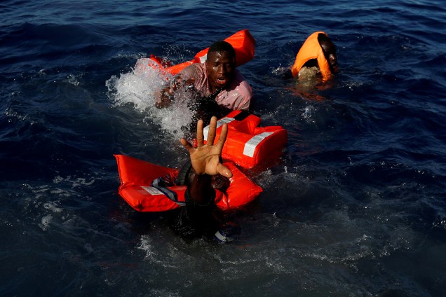 Migrante pede socorro antes de colocar colete salva-vidas, durante operação de resgate na costa de Zawiya, na Líbia - 14/04/2017