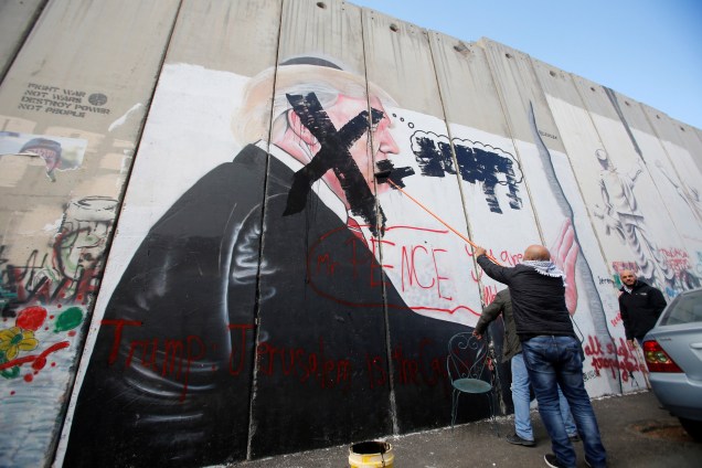 Palestino pixa um mural com a imagem do presidente dos Estados Unidos, Donald Trump, em uma parte da barreira israelense, na cidade de Belém, na Cisjordânia - 07/12/2017