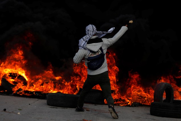 Manifestante palestino lança pedras contra as tropas israelenses durante confronto em um protesto contra a decisão do presidente dos Estados Unidos, Donald Trump, de reconhecer Jerusalém como a capital de Israel - 07/12/2017