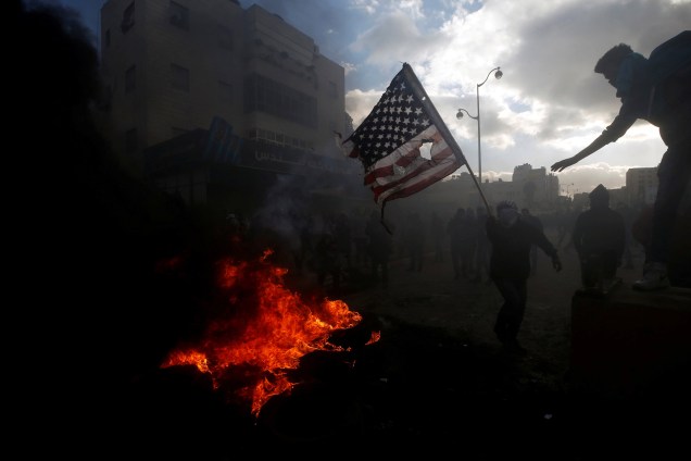 Manifestante palestino queima uma bandeira dos Estados Unidos durante confrontos com tropas israelenses perto do assentamento judeu de Beit El, perto da cidade de Ramallah, na Cisjordânia - 07/12/2017