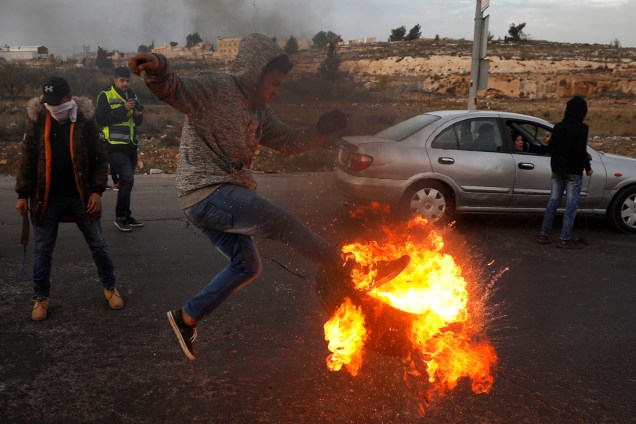 Palestino chuta pneu em chamas durante confronto com tropas israelenses, em protesto realizado contra a decisão do presidente dos Estados Unidos, Donald Trump, de reconhecer Jerusalém como a capital de Israel - 10/12/2017