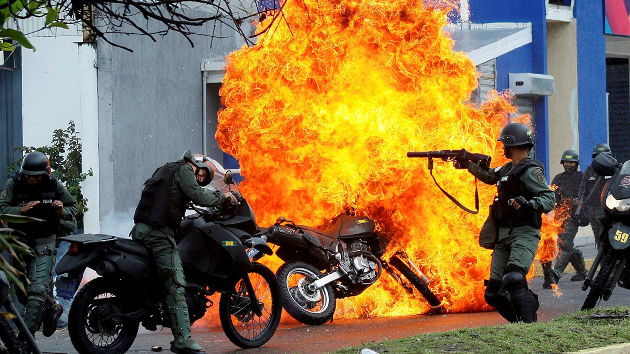 Membros das forças de segurança venezuelanas reprimem manifestantes enquanto motocicleta é incendiada, durante protestos contra o presidente Nicolás Maduro, em San Cristobal - 29/05/2017