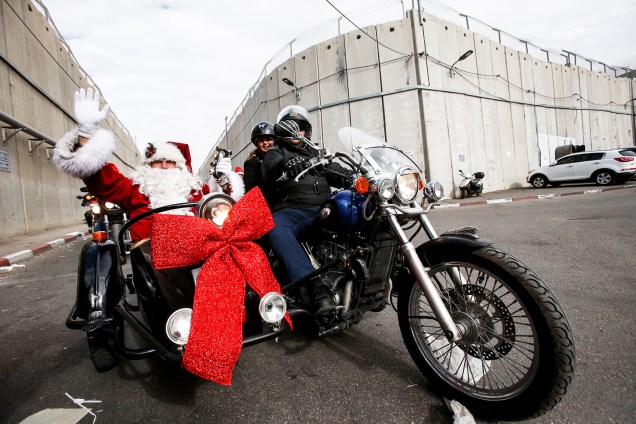 Homem vestido de Papai Noel acena para pedestres em uma motocicleta, na cidade de Belém, localizada na Cisjordânia - 24/12/2017